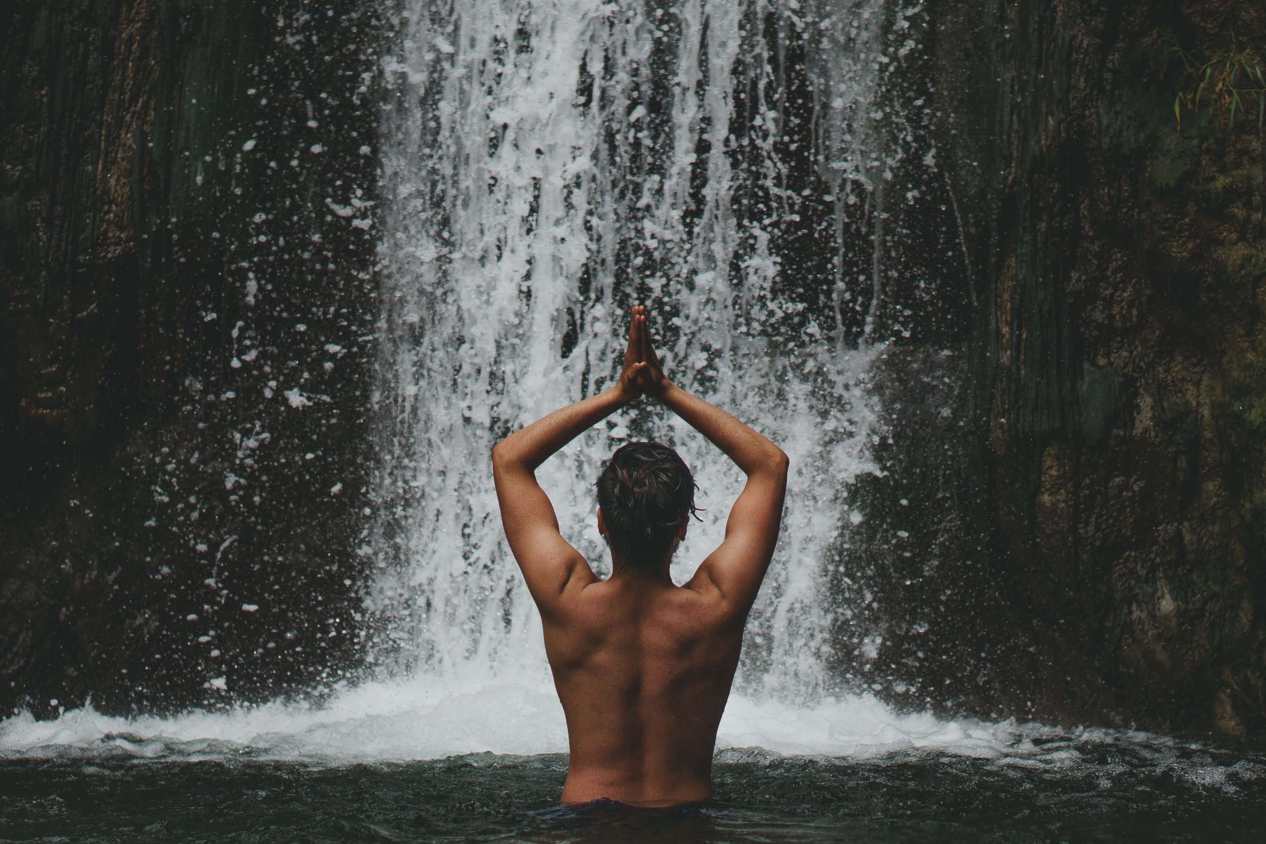 person standing under waterfall to show spine back